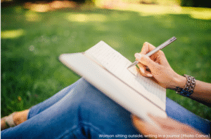 Woman sitting outside writing in a journal