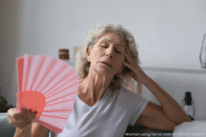 Woman using fan to cool off during heat wave