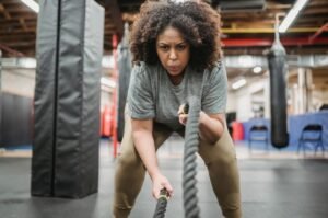 Determined woman exercising with battle ropes in gym