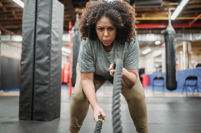 Determined woman exercising with battle ropes in gym