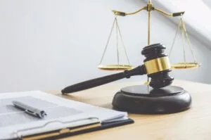 Scales of justice, gavel, and law book in a courtroom.