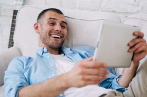 Man reading on tablet while relaxing on sofa