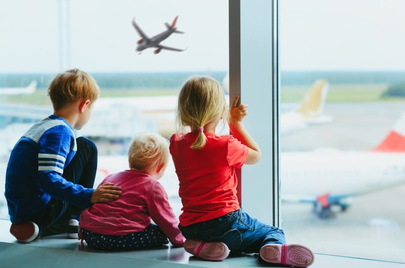 Family travel: kids at airport watching airplane land