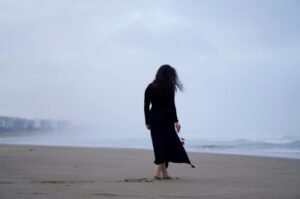 A lone woman walks along a quiet beach following a deadly shooting that left Sydney, Australia in mourning.