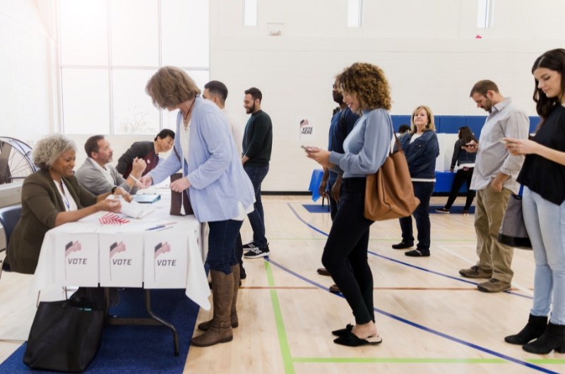 Voters line up at a local polling location as election officials verify identification during check-in.