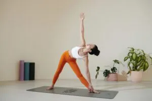 Woman practices yoga stretching on a yoga mat.