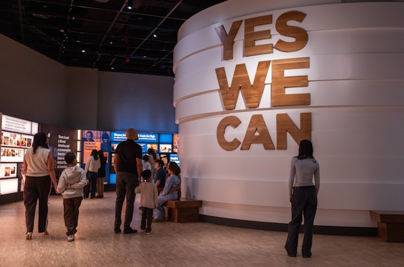 Visitors explore the museum inside the Obama Presidential Center in Chicago, where the iconic "Yes We Can" rallying cry greets guests at the heart of the exhibition space.
