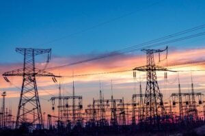 High-voltage transmission lines carry electricity across the U.S. power grid as extreme summer heat prompts emergency measures to maintain reliable service.