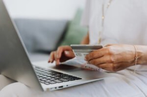 A woman uses a credit card while shopping online as Americans carry nearly $1.25 trillion in credit card debt.