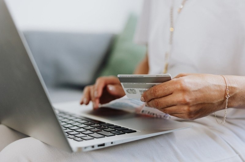 A woman uses a credit card while shopping online as Americans carry nearly $1.25 trillion in credit card debt.