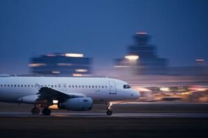 A cargo aircraft moves along an airport runway at dusk.