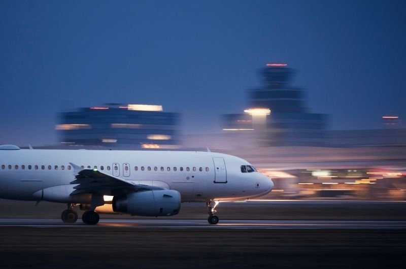 A cargo aircraft moves along an airport runway at dusk.