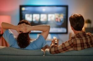 A couple watches television at home as Skydance’s newly expanded entertainment portfolio brings some of America’s biggest movie, television, news and streaming brands under one company.