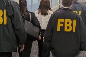 Wanying “Heather” Zhang is escorted by FBI agents following her arrest at Los Angeles International Airport on Oct. 4, 2026. Federal authorities accuse her of acting as an unregistered agent of China.